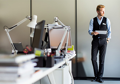 Symbolbild: Lässiger Geschäftsmann in seinem Büro, der einen Bericht prüft